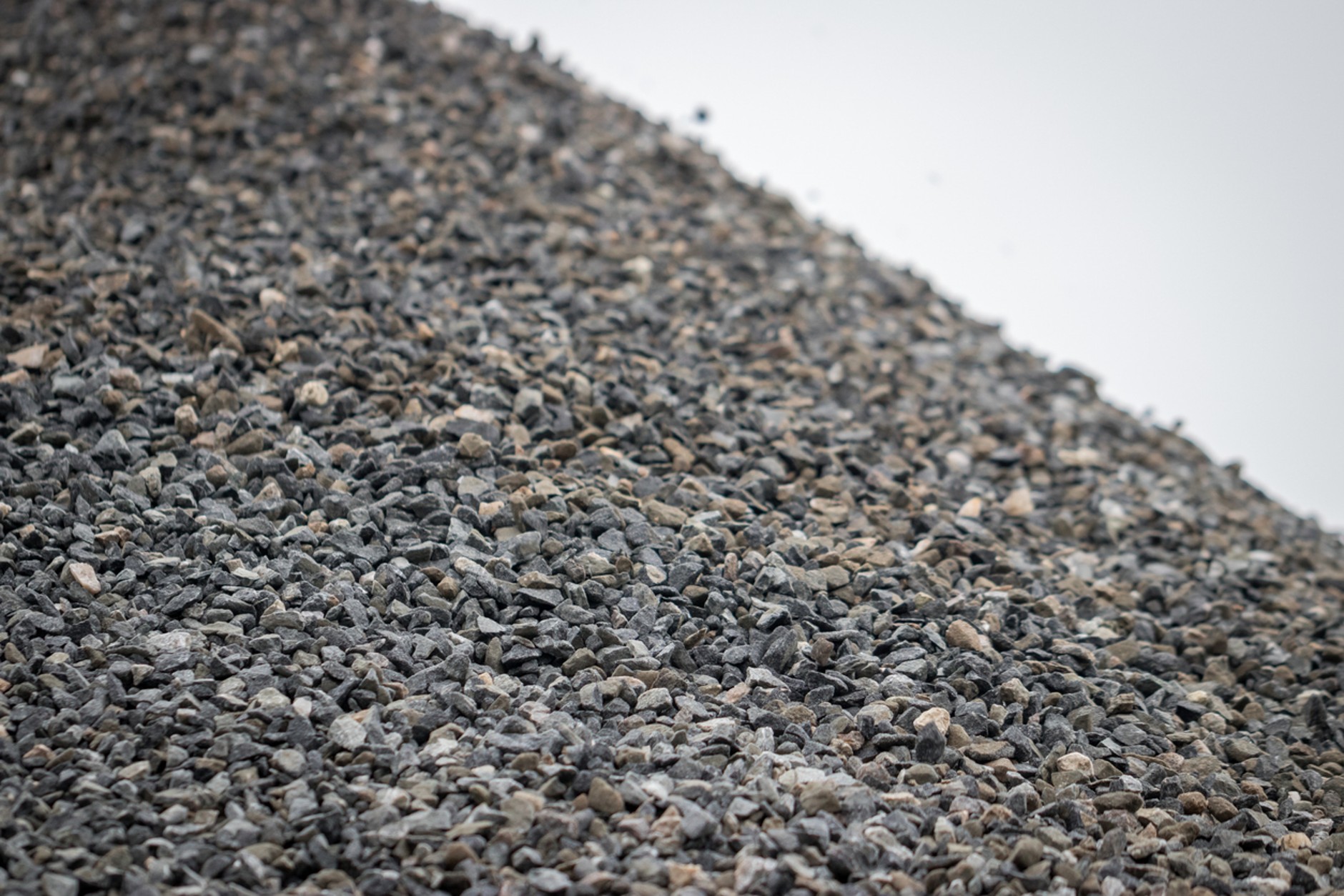 Close-up of a stockpile of grey crushed stone aggregate, showing angular gravel particles commonly used for drainage, road construction, foundations, and groundworks.
